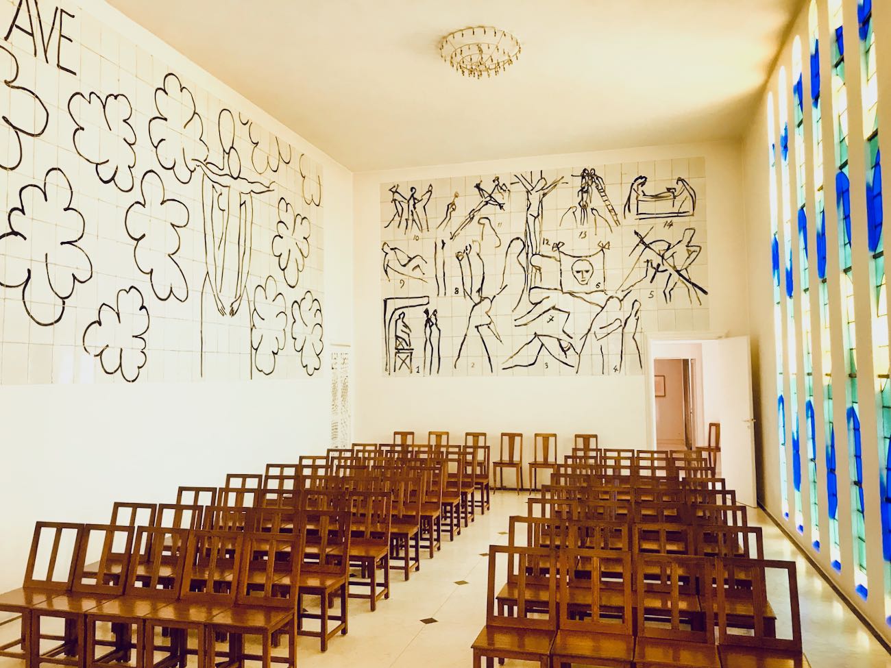 Interno della Chapelle du Rosaire con vetrate blu e verdi e murales di Matisse